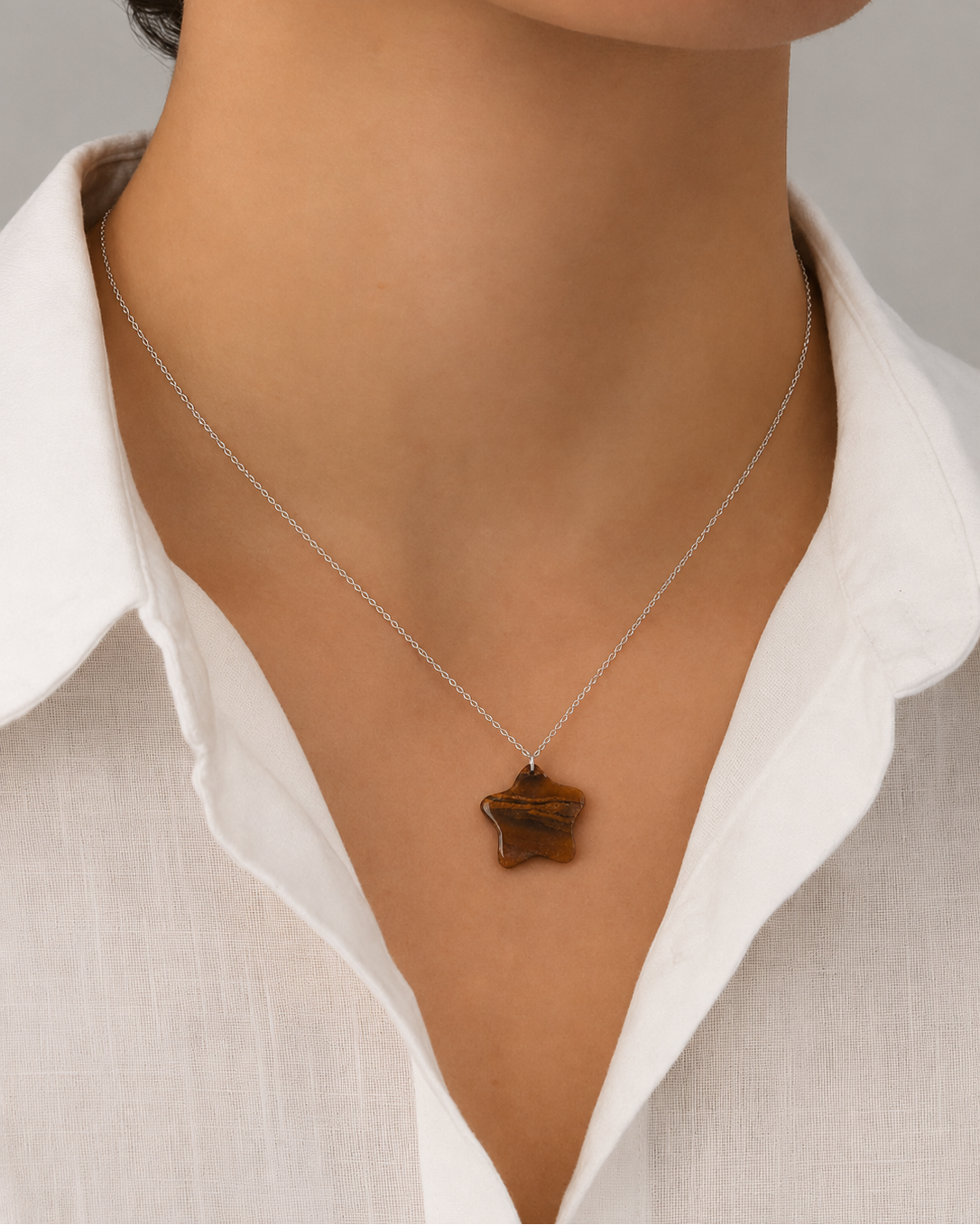Natural Tiger Eye star pendant necklace on silver chain over white fabric