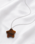 Model wearing natural Tiger Eye star pendant necklace with white shirt, close-up