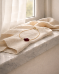 natural garnet bracelet on gold chain placed on beige fabric surface minimal jewelry