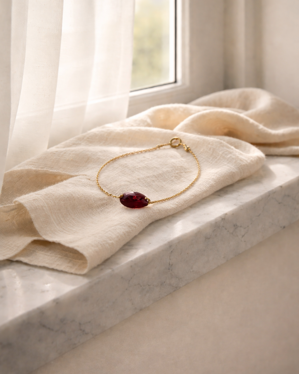 natural garnet bracelet on gold chain placed on beige fabric surface minimal jewelry