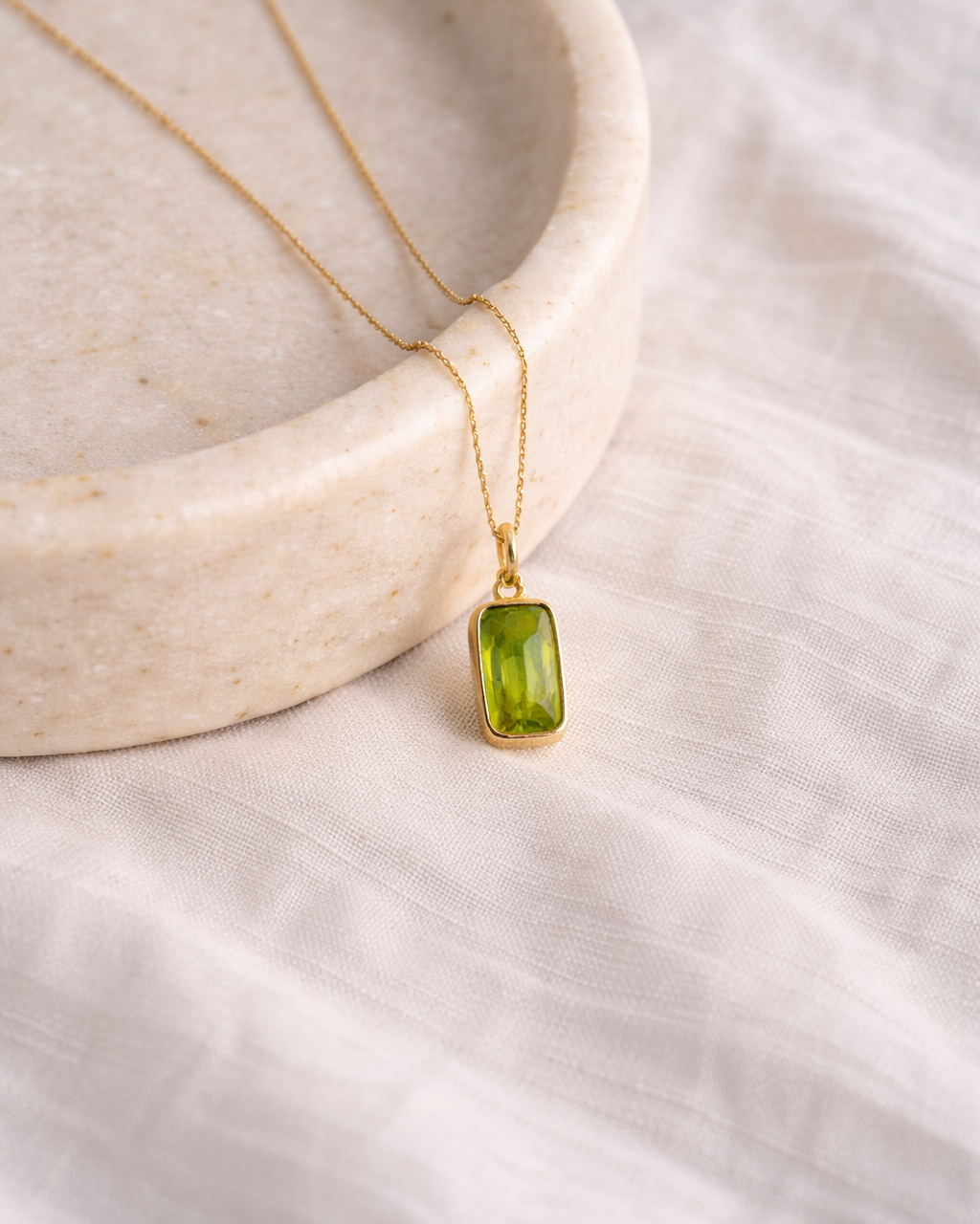 close up of peridot rectangle pendant on gold chain showing natural green stone