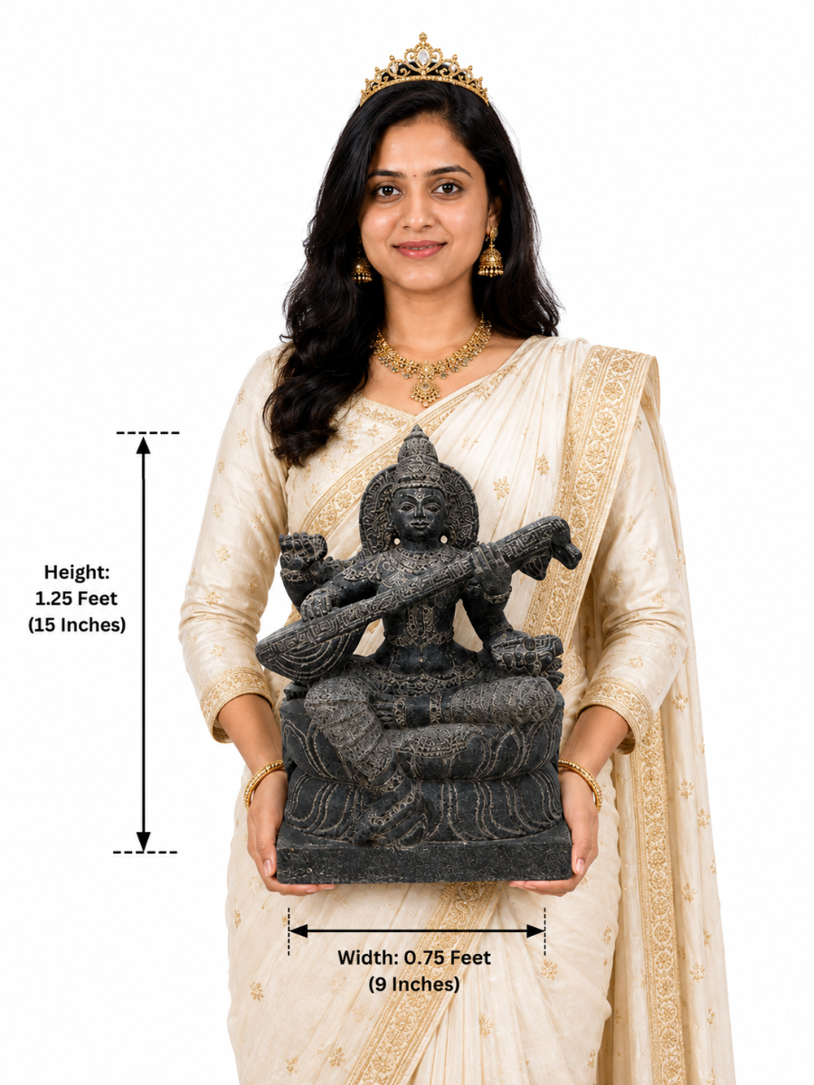 Hand-carved 1.25 ft Saraswathi Devi statue in polished black stone shown beside an adult model for scale.