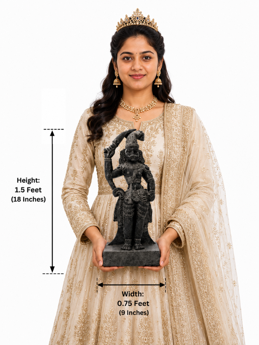 Hand-carved 1.5 ft Madurai Veeran guardian deity statue in polished black stone shown with an adult model for scale.