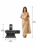 Hand-carved Shiva Lingam in polished black stone shown beside an adult model for scale with measurements on a white background.