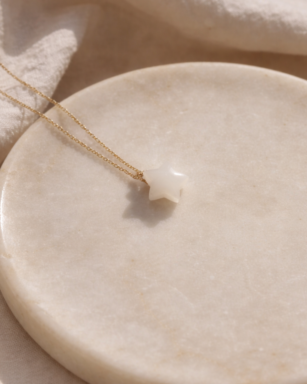 close up of white moonstone star pendant on gold chain showing natural texture