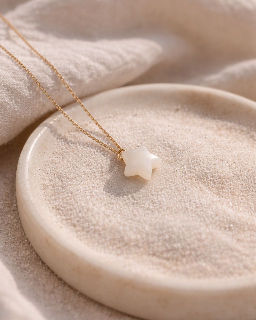 white moonstone star pendant necklace on gold chain placed on beige surface